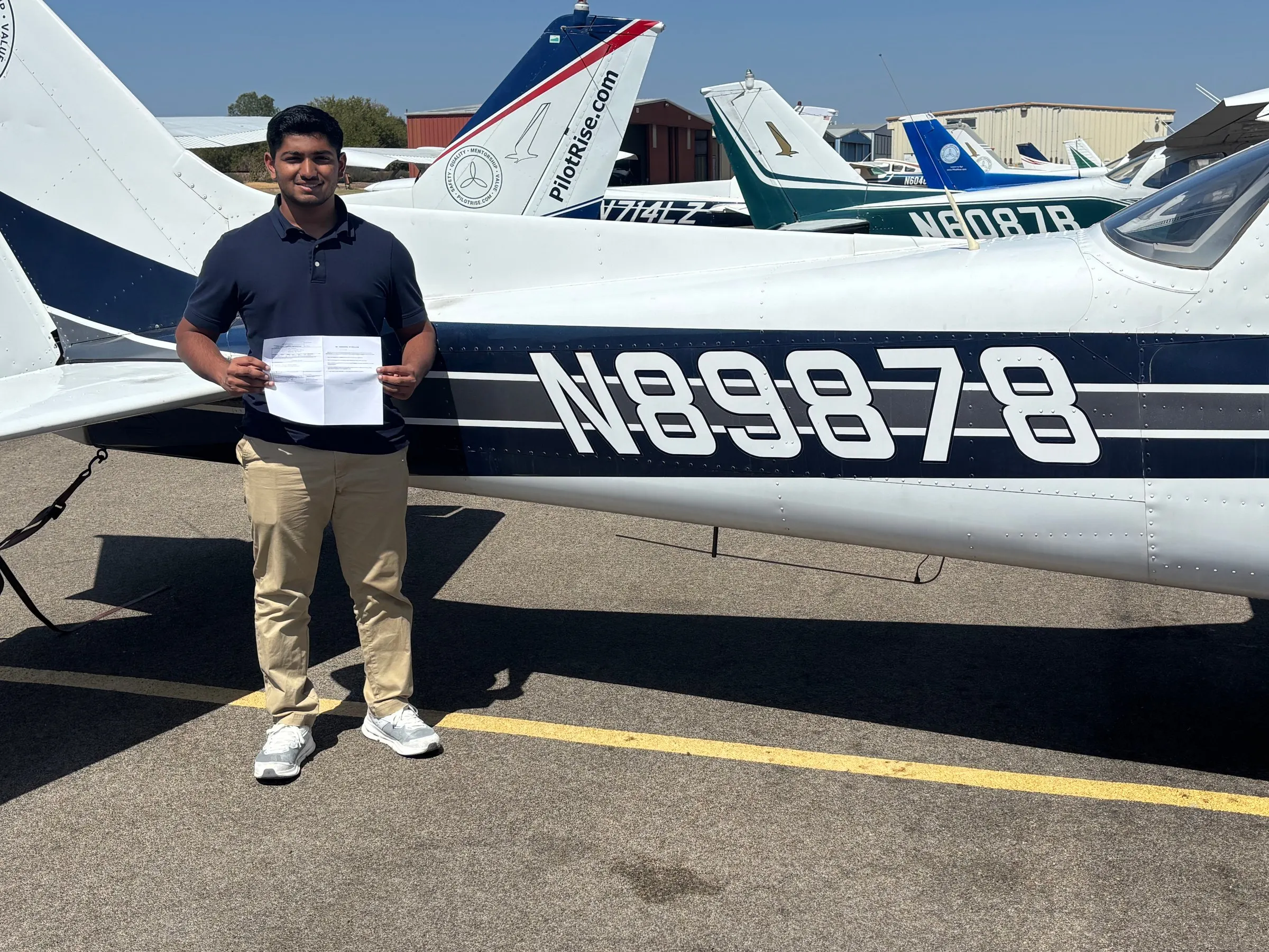 Student holding paperwork beside a Pilot Rise training aircraft