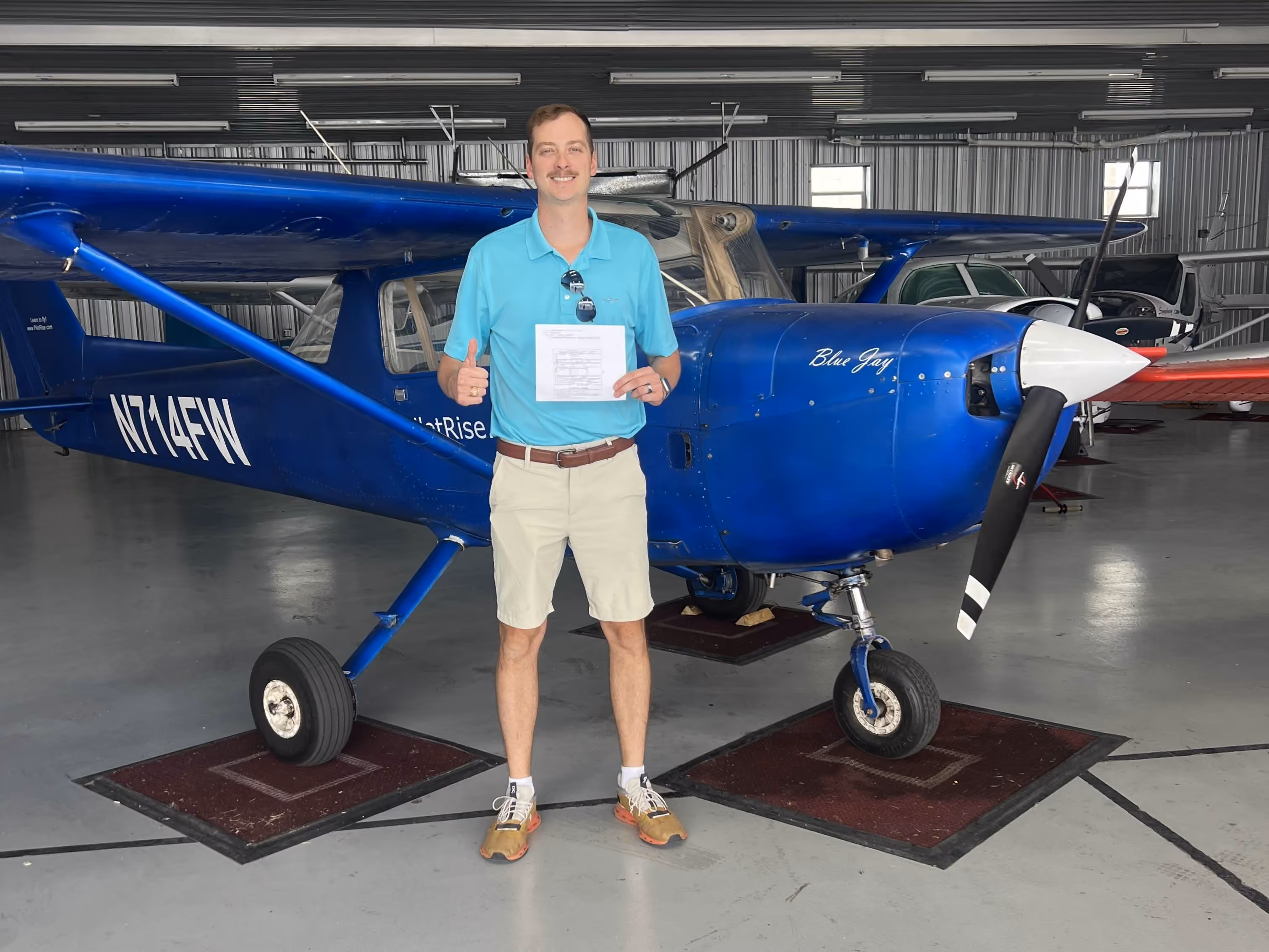 College Credit hero image with a Pilot Rise pilot holding a completed checkride certificate in front of a blue Cessna
