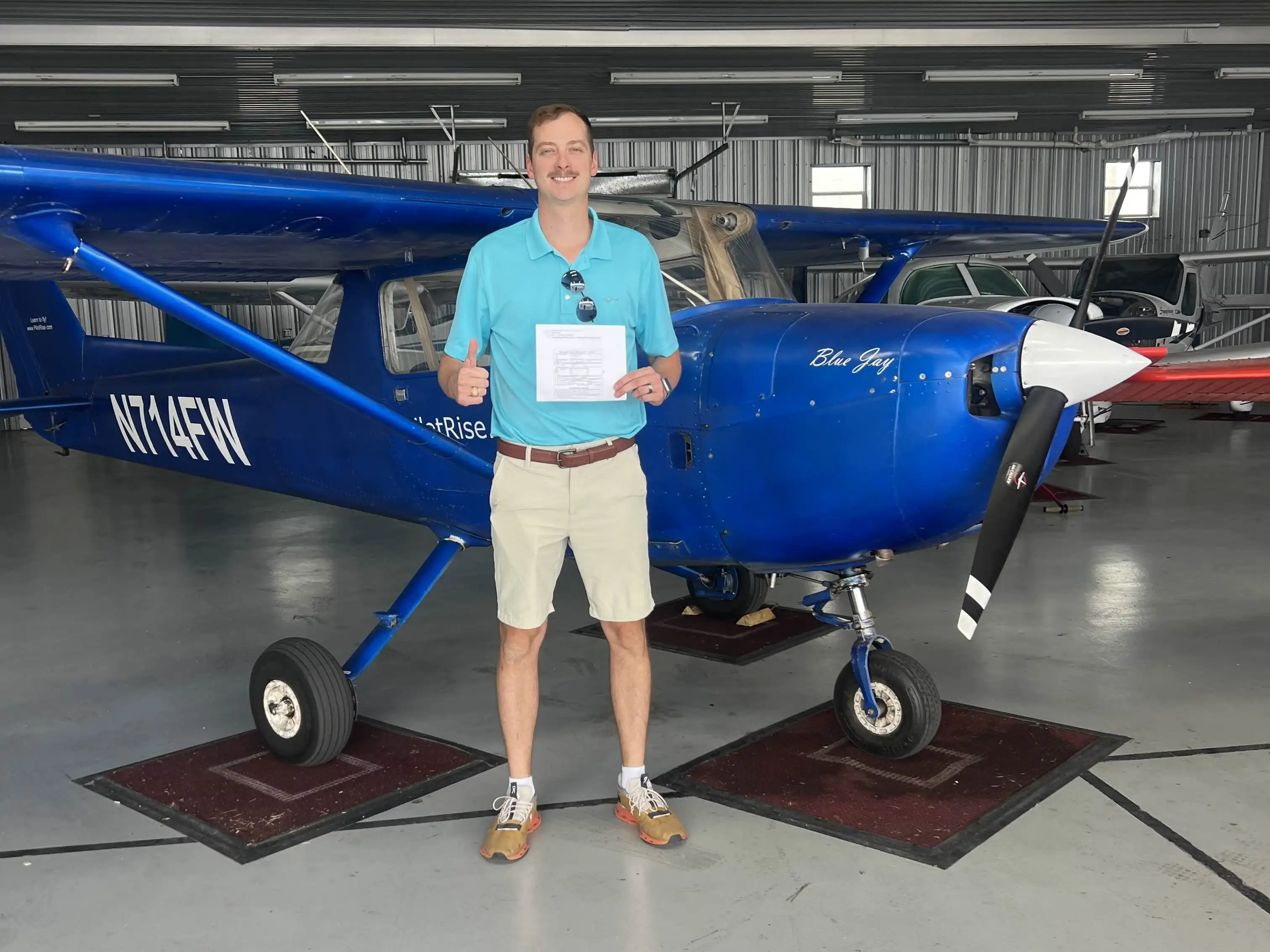 College Credit hero image with a Pilot Rise pilot holding a completed checkride certificate in front of a blue Cessna